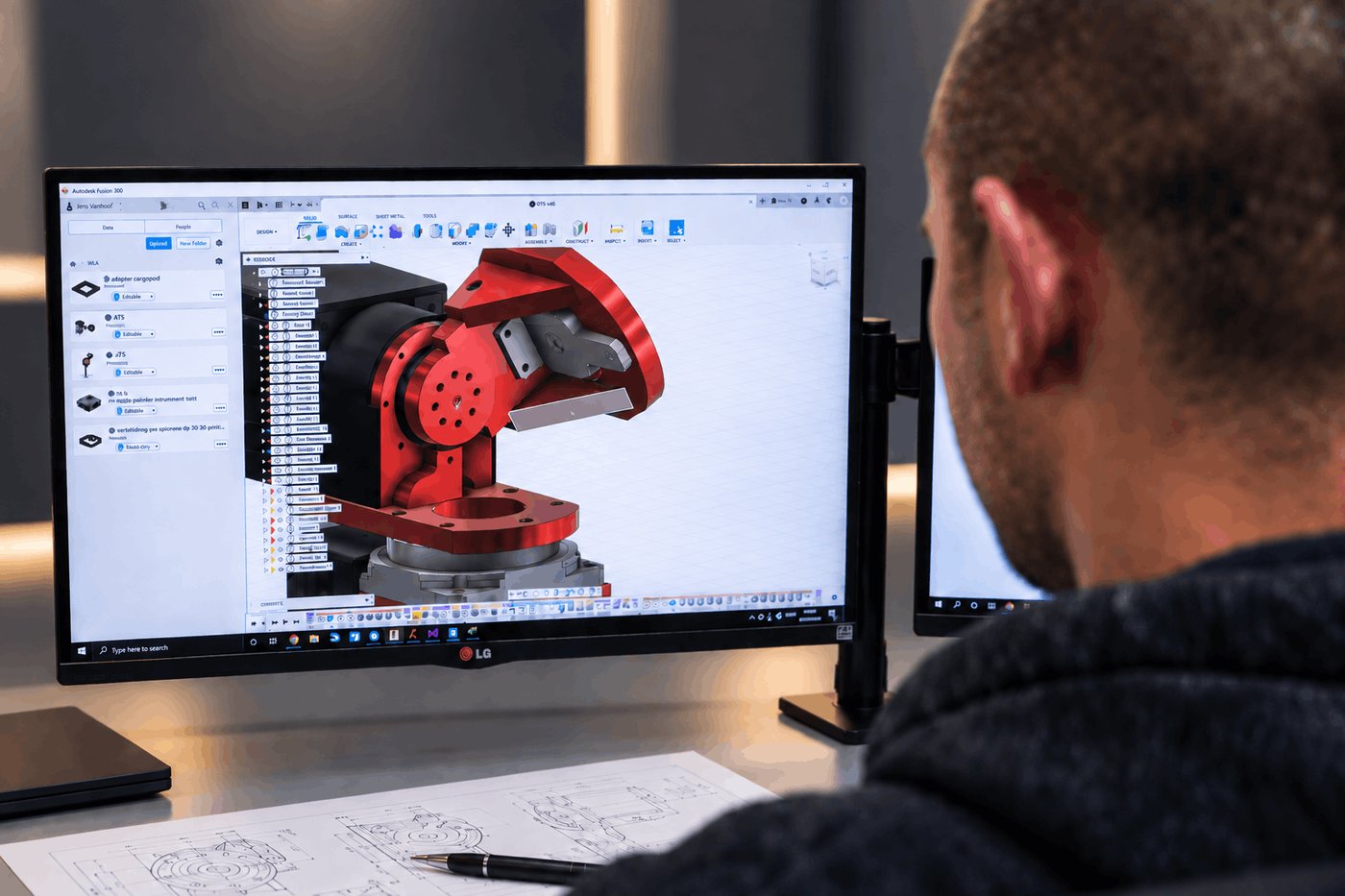 WorldLinX engineer designing the auto-tracking antenna pedestal in CAD, with printed engineering drawings on the desk